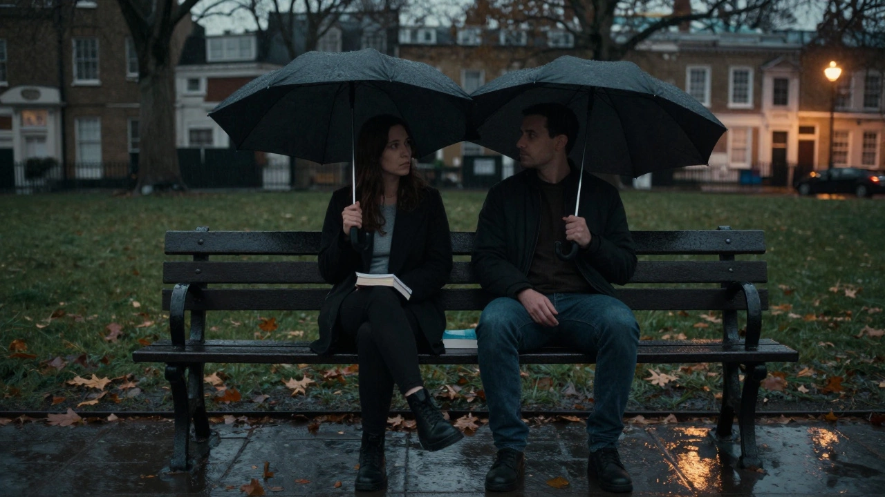Two people sitting side by side on a rainy London park bench, sharing quiet space under an umbrella.
